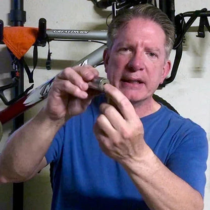 Man in blue shirt holding socket tool in garage with bicycle in background